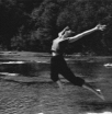 a girl jumping into the creek with arms and legs extended